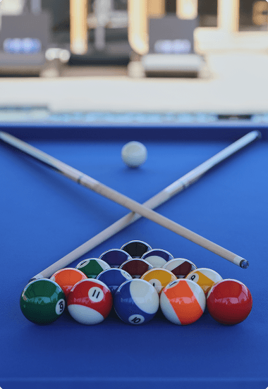 Classic pool table with billiard balls arranged and two cue sticks ready for a game