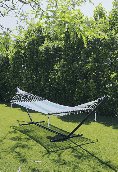 Hammock suspended between trees in a grassy field, offering a peaceful spot for relaxation