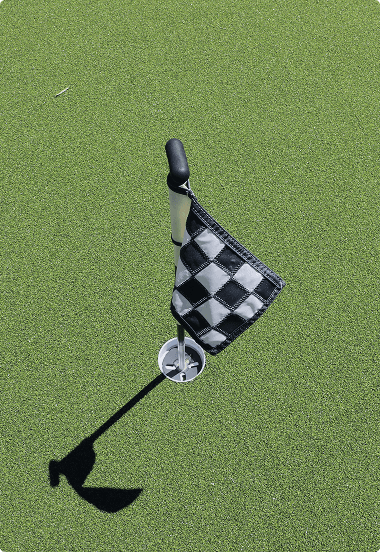 Black and white checkered flag on a green putting green, marking the golf hole
